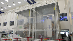 A large, cleanroom facility with two enclosed workstations housing space equipment labeled 
